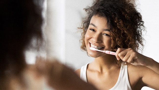 a person brushing their teeth in the mirror and smiling