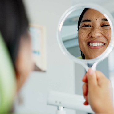 Woman smiling at reflection in dentist office
