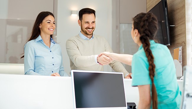 husband shaking front desk members hand