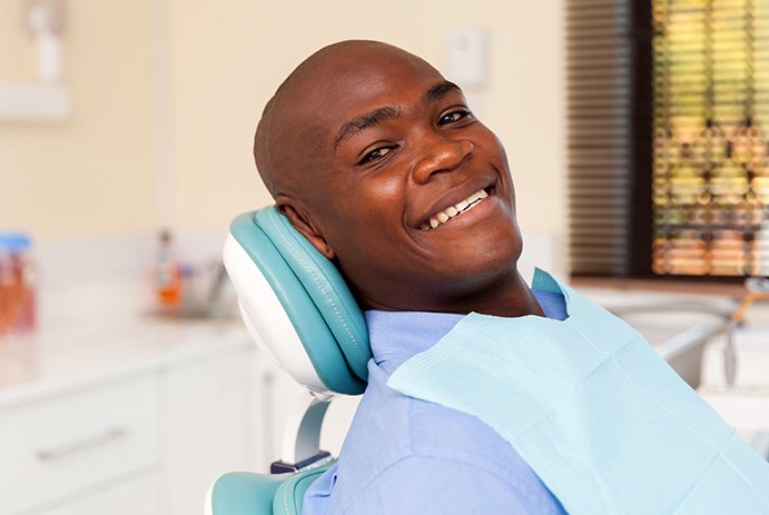 man smiling bright in exam chair