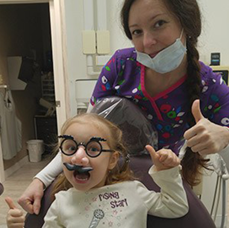 team member and young girl with funny face doing thumbs up