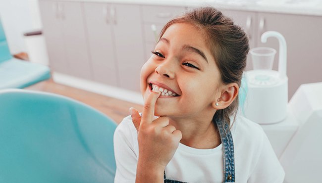 young girl pointing to teeth