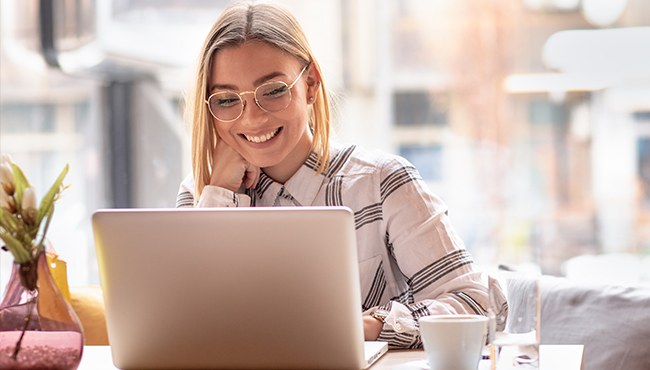 young woman smiling and working on laptop