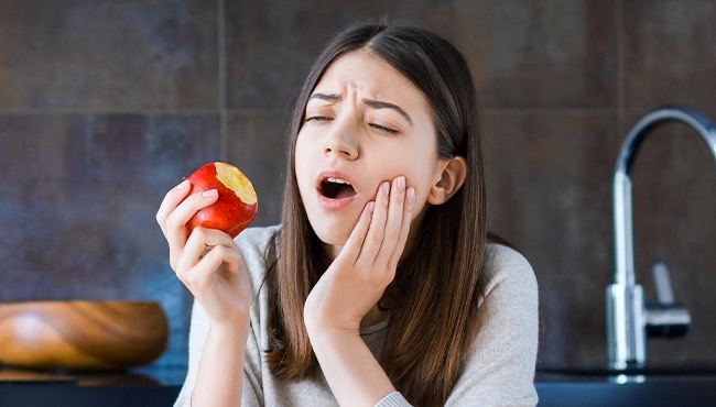 woman eating apple in pain