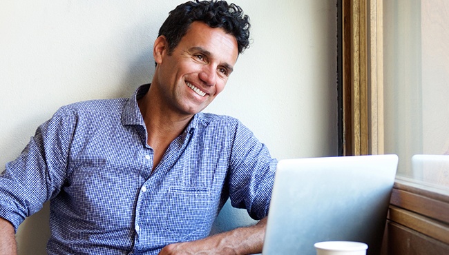 man smiling at cafe with laptop