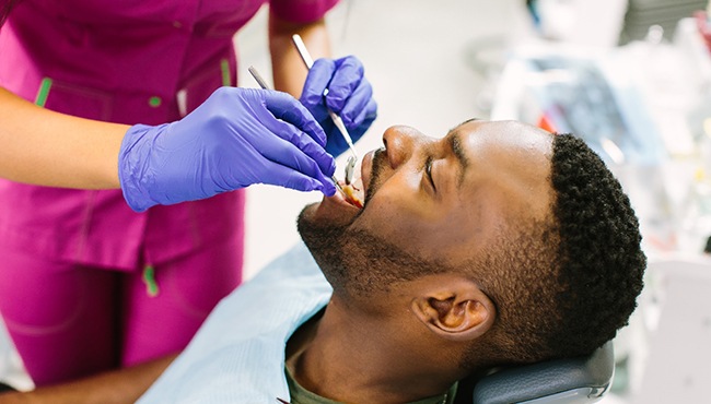 Patient reclining in dental chair, attending routine exam