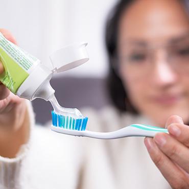 Woman preparing to brush teeth, hoping to prevent gum disease