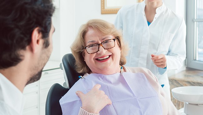 woman with glasses smiling at dentist
