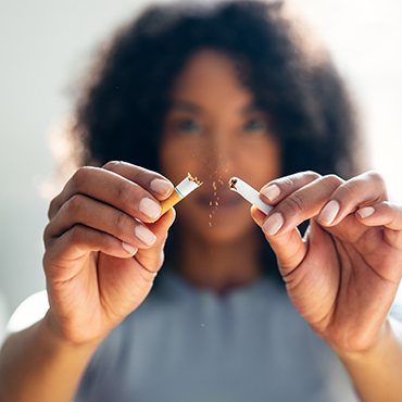 A woman breaking a cigarette into tiny pieces