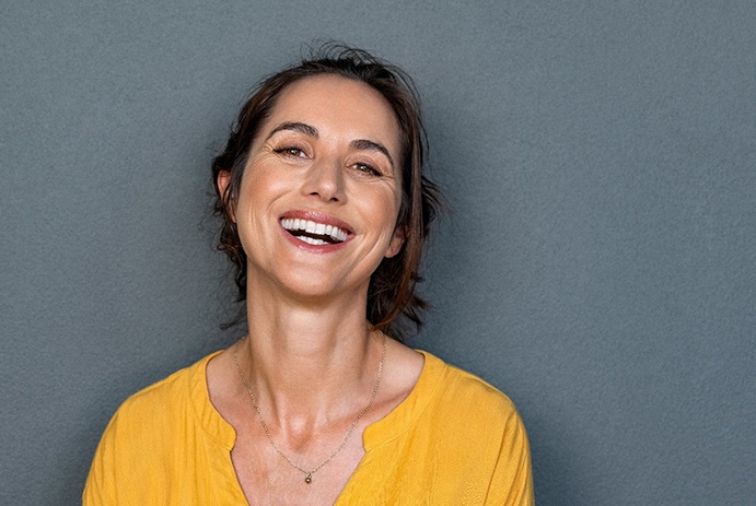 Middle-aged woman smiling with her implant dentures in Buffalo Grove