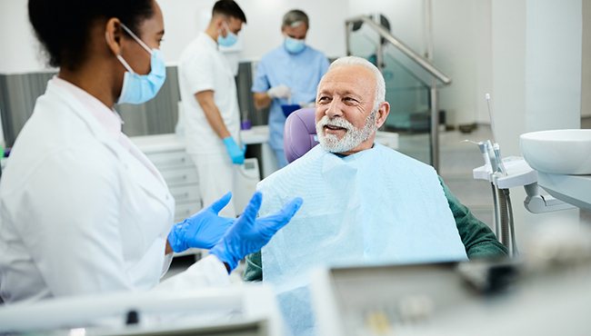 Senior dental patient learning about his candidacy for implant dentures