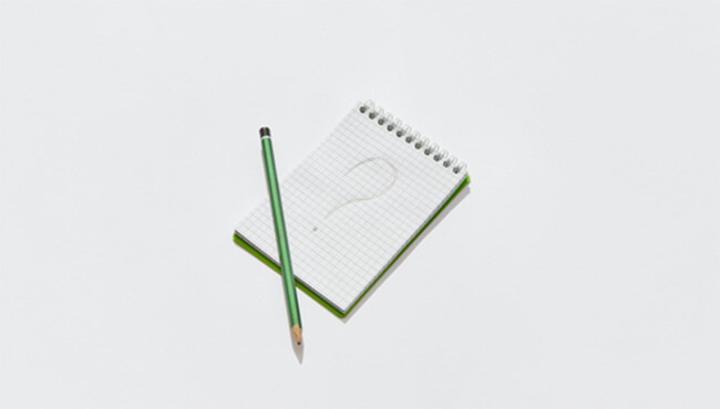 Question mark on notepad and green pencil