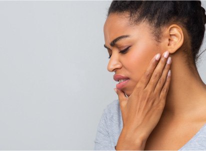 woman holding cheek in pain