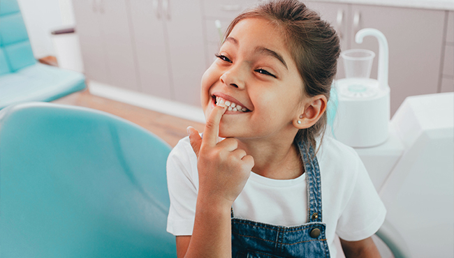 young girl pointing to top teeth