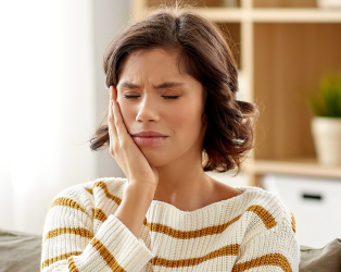 woman closing eyes and holding cheek