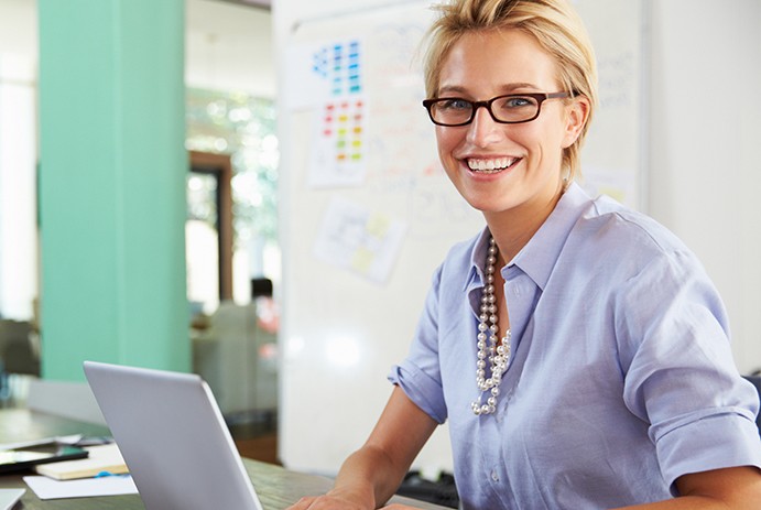 woman smiling while working on computer