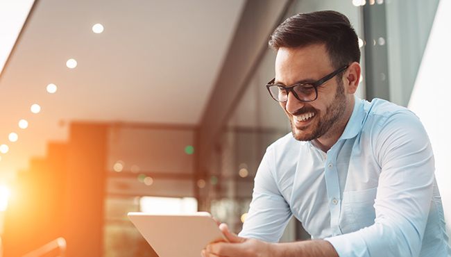 man smiling while working on tablet