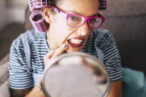 person looking at their gums in mirror 