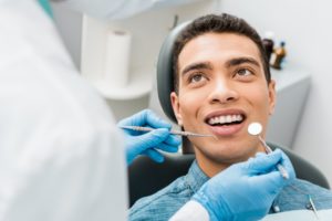 a dentist examining a patient’s smile with a dental mirror