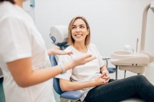 a woman smiling while speaking with her cosmetic dentist