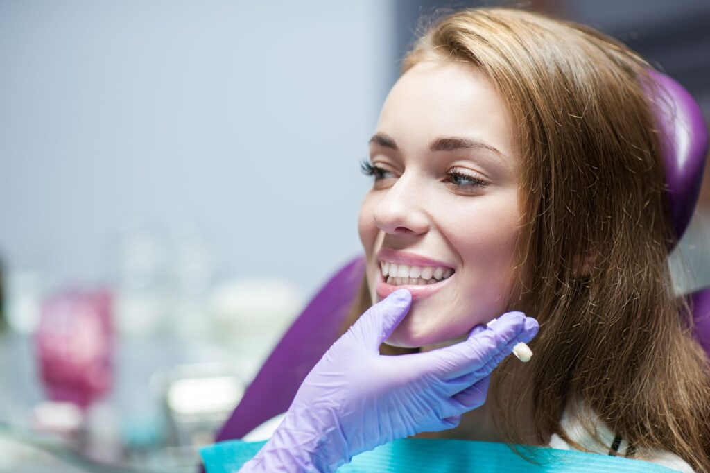 Woman in purple dental chair smiling at dentist in purple gloves