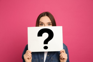 Woman covering her mouth with a large card that has a question mark on it