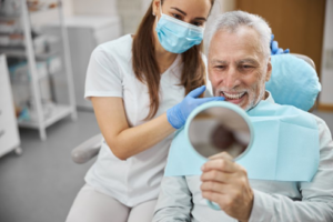 Patient examining new implant denture with dentist nearby